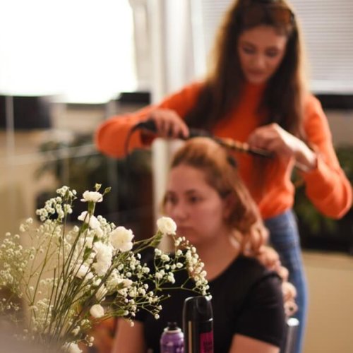 Vizážistka Elicolay Makeup upravuje vlasy klientke počas prípravy na špeciálnu udalosť.